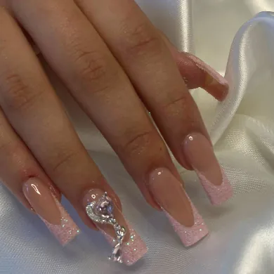 Long square nails with pink glitter French tips and a crystal heart charm